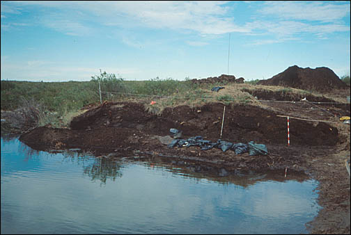 Une butte de terre sur le site de fouille archéologique au bord de l'eau.