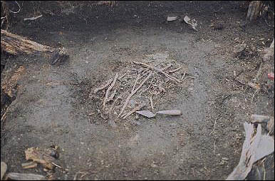 Tas de brindilles et de branches au fond de la fosse archéologique.