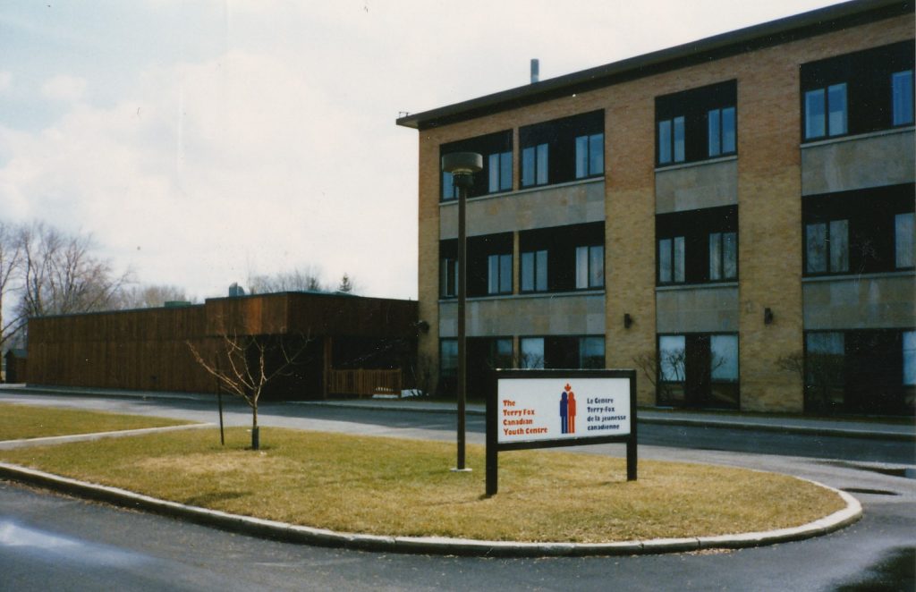 Un bâtiment en briques de trois étages avec de nombreuses fenêtres. Une enseigne à l’avant indique « Le Centre Terry Fox de la jeunesse canadienne ».