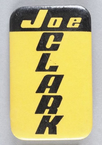 Macaron jaune et noir avec Joe écrit horizontalement et Clark écrit verticalement.