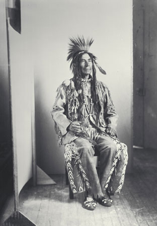 Nlaka'pamux (Thompson) Chief John Tetlenitsa in traditional clothing and holding a war club, Ottawa, Ontario, © CMC/MCC, J.A. Teit, 35996