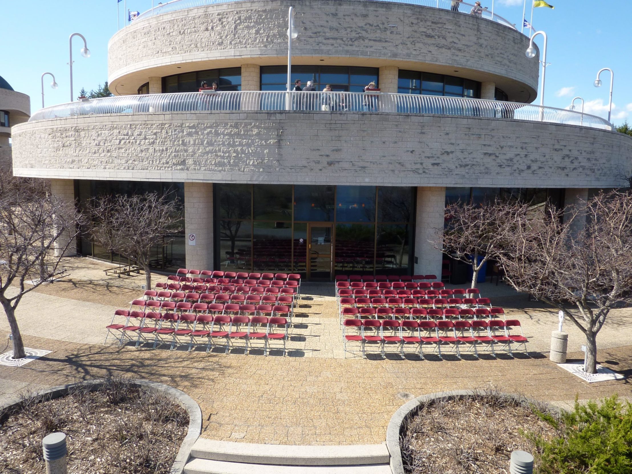 A circular building with red chairs in front of it.