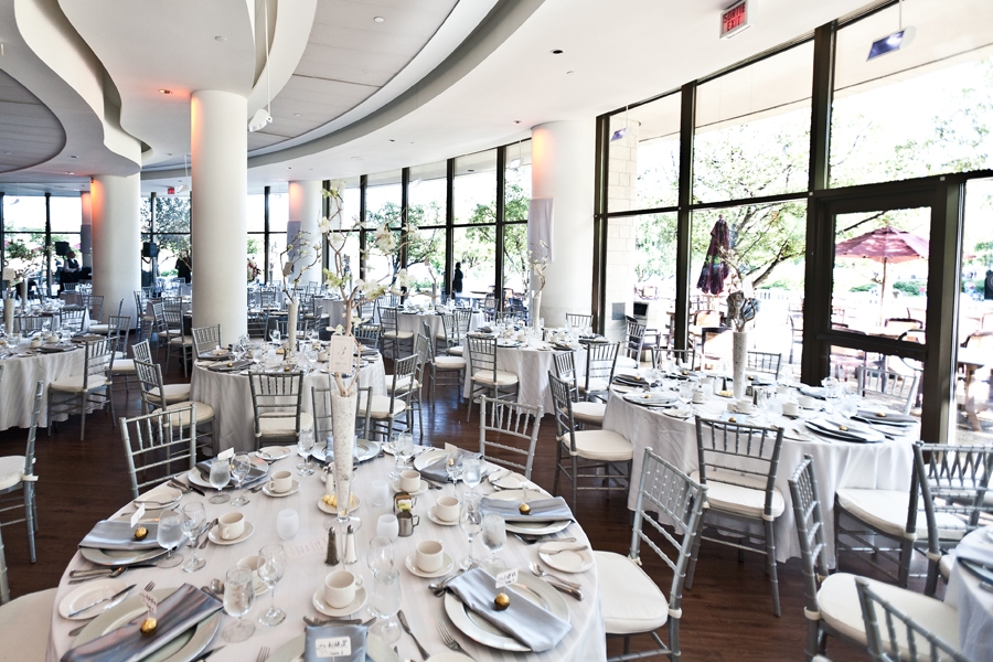 A room with tables and chairs set up for a wedding reception.