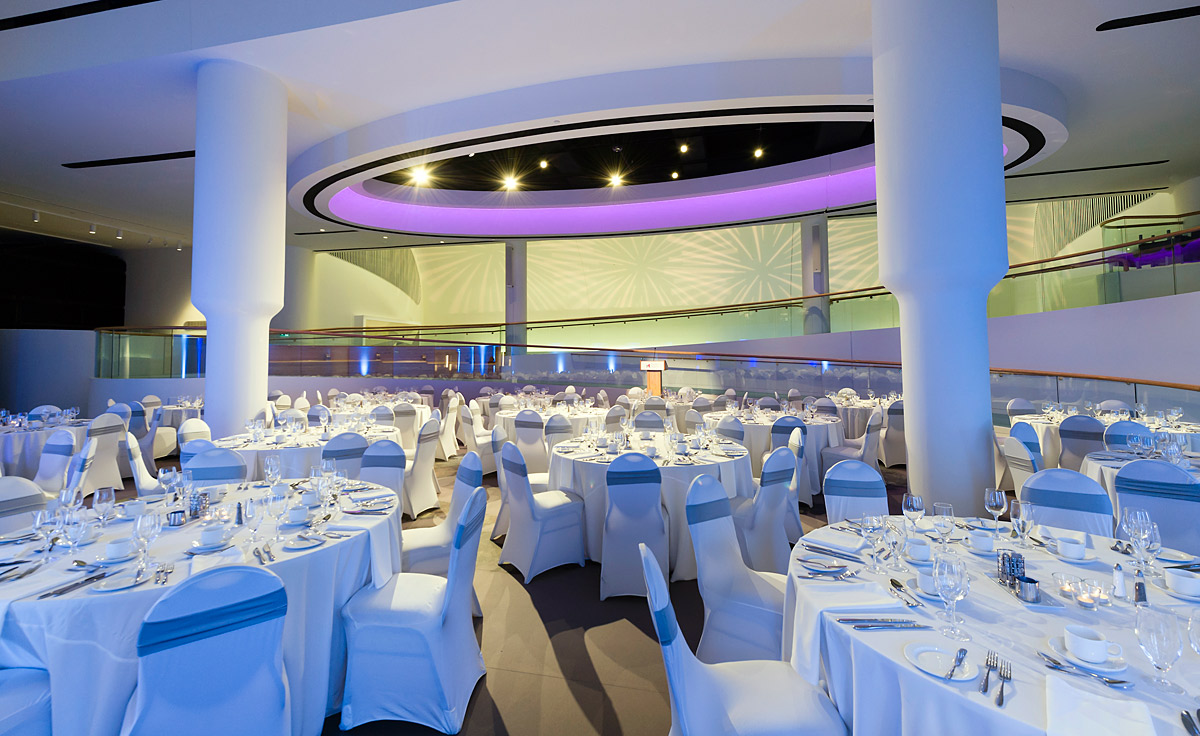 Le Musée canadien de l'histoire, situé à Ottawa, présente une grande salle remplie de tables et de chaises blanches.