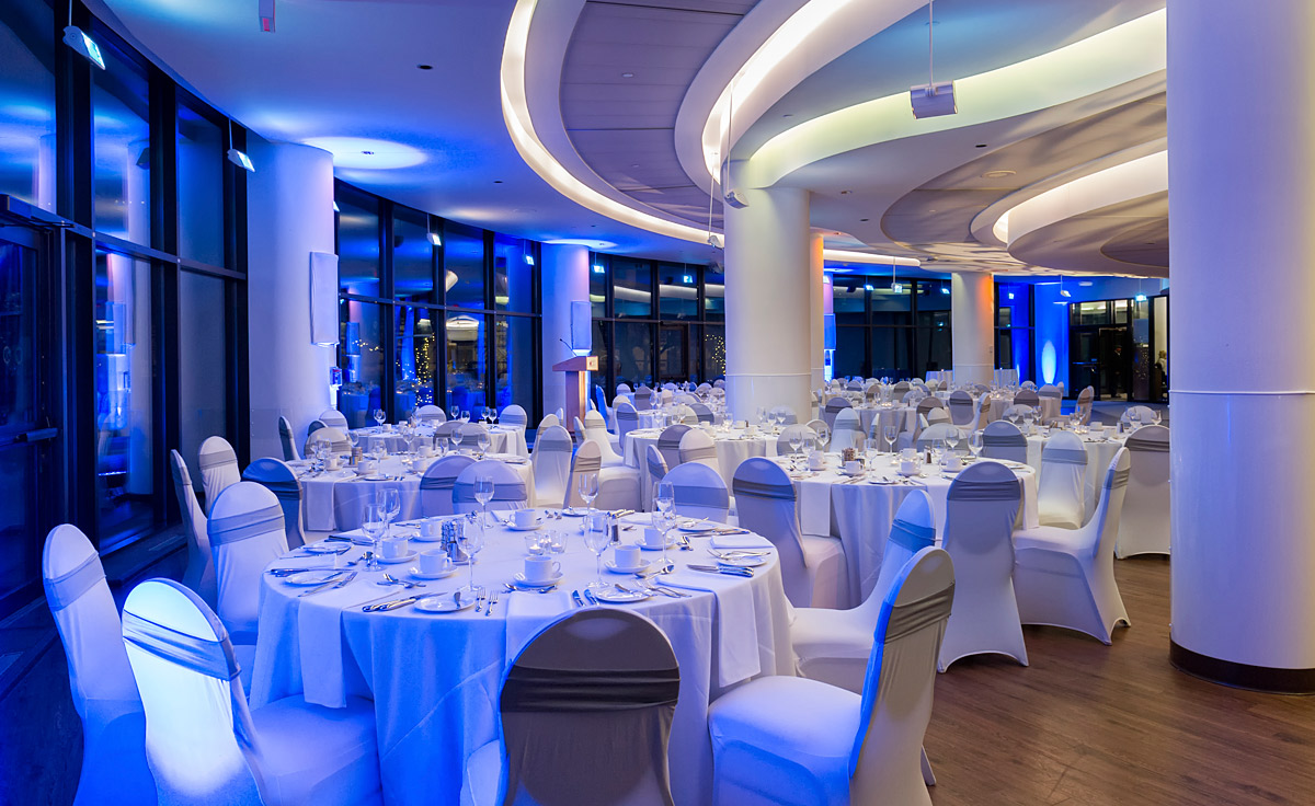 Une salle de banquet avec des tables blanches et des lumières bleues située à Ottawa au Musée canadien de l'histoire.