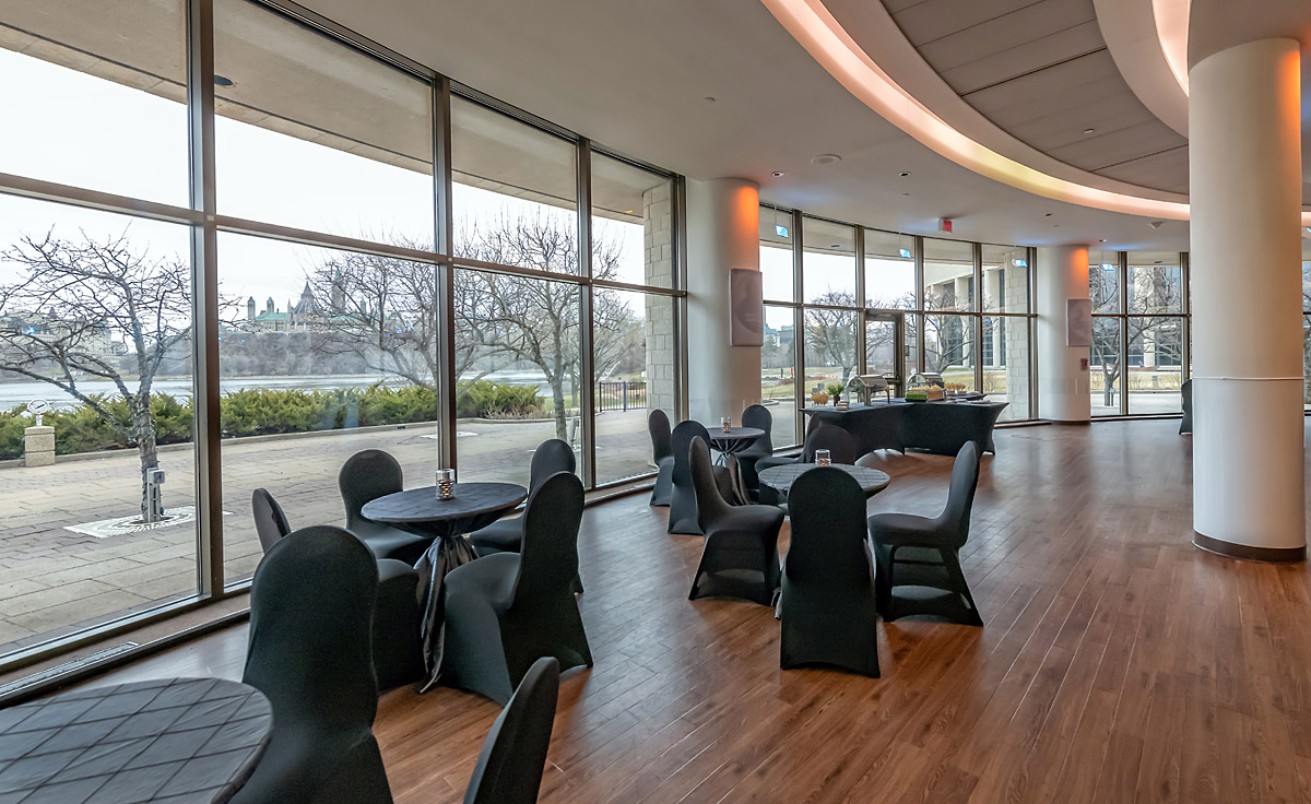 Une grande salle avec de grandes fenêtres et des tables noires située à Ottawa au Musée canadien de l'histoire.