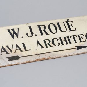 Enseigne blanche avec lettrage noir indiquant « W. J. Roué Naval Architect. »