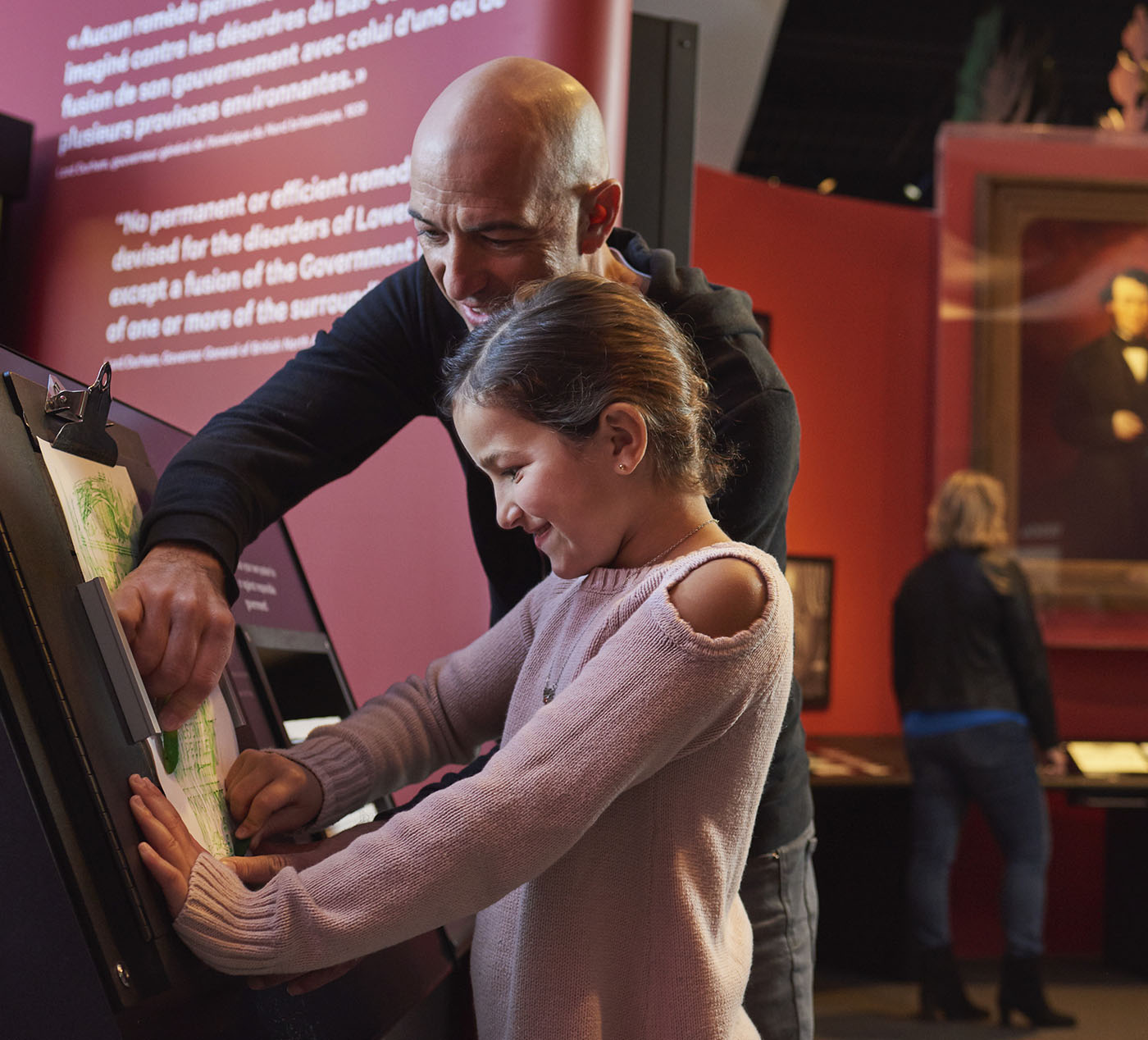 Un homme et une fille regardant une exposition au Musée canadien de l’histoire.