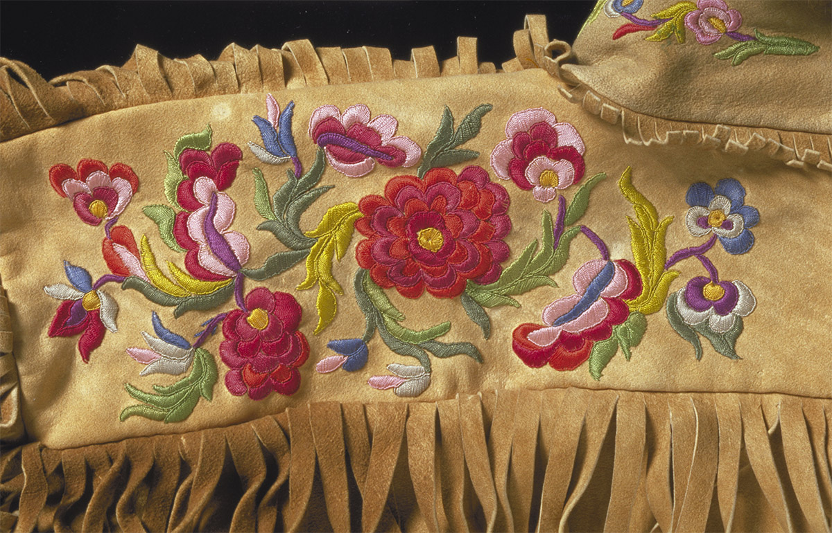 Une couverture beige avec des fleurs et des franges brodées exposée au Musée canadien de l'histoire à Ottawa.