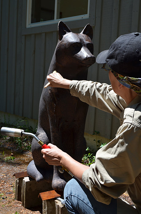 Une femme peignant une statue de loup au Musée canadien de l'histoire à Ottawa.