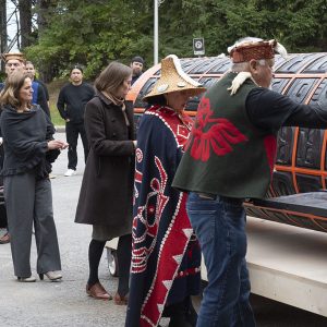 Un groupe de personnes fait la queue près du monument. Certaines d’entre elles tendent la main pour toucher sa surface.