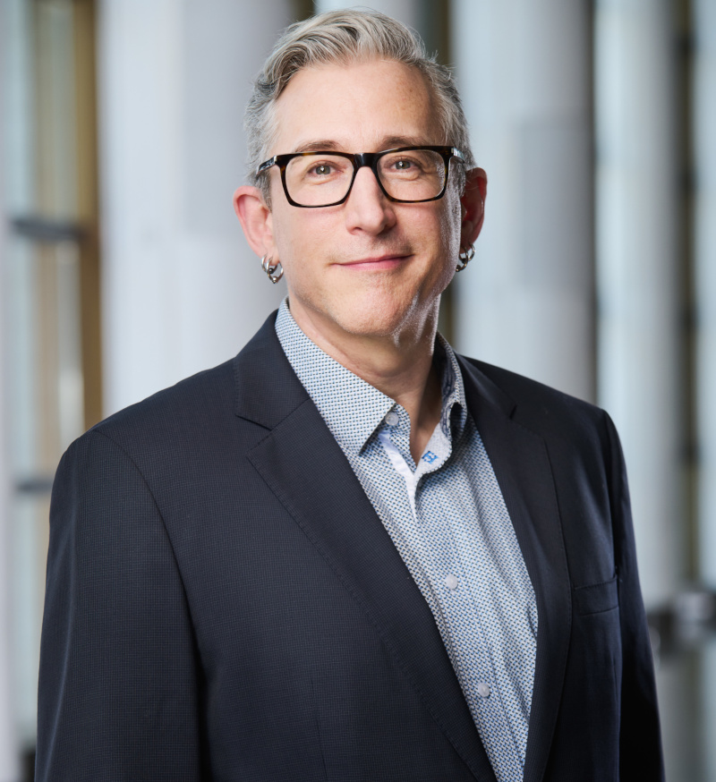 A very light-skinned adult man with short, greying hair and glasses.