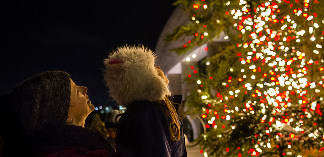 Une femme et un enfant regardant vers le sapin de noël