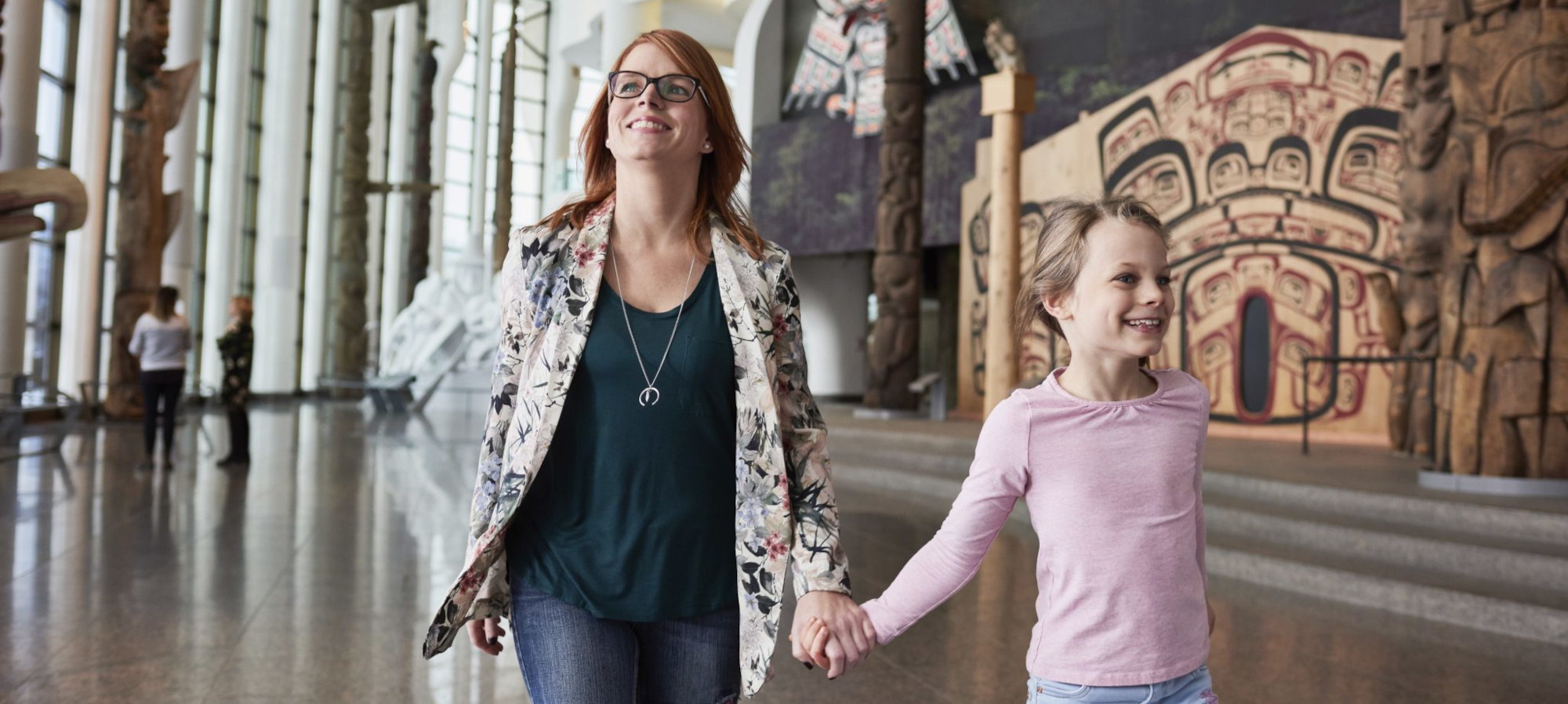 Une femme et un enfant marchent main dans la main dans un musée, entourés de diverses œuvres d'art et expositions.